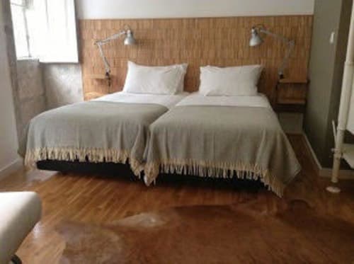 Estúdio PortoSense Ribeira com camas geminadas, cabeceira de madeira, roupas de cama brancas e vista para o rio no Porto