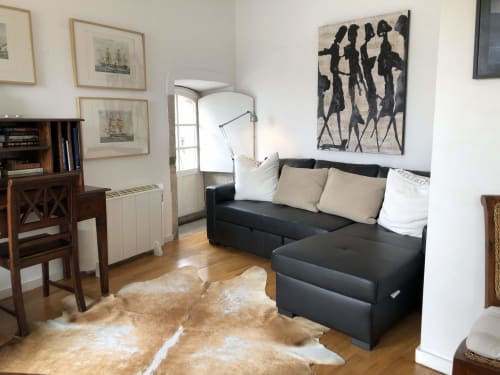 Sala de estar duplex PortoSense Ribeira com sofá seccional preto, móveis de madeira e arte moderna no Porto, Portugal