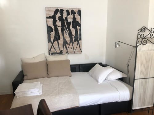 Quarto duplex PortoSense Ribeira com cama preta, roupa de cama branca, almofadas bege e obra de arte moderna