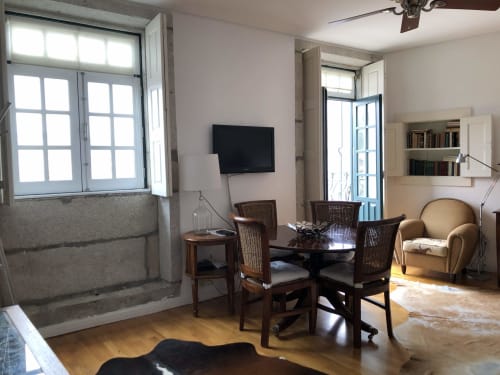 Espaçosa sala de estar no PortoSense Ribeira Duplex com vista para o rio, mobiliário em madeira, TV e luz natural