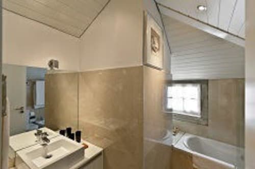 Banheiro moderno do apartamento PortoSense Ribeira no Porto com pia, banheira, chuveiro e janela com luz natural