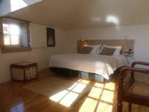 Quarto espaçoso com cama de casal, móveis em madeira, piso de madeira e janelas iluminadas no PortoSense Ribeira Duplex, Porto