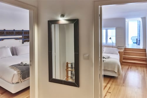 Corredor do apartamento PortoSense Almada com espelho e portas de quartos abertas revelando camas e pisos de madeira