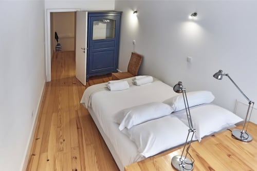 Quarto moderno na PortoSense Almada no Porto com duas camas, roupa de cama branca, assoalho de madeira e iluminação contemporânea