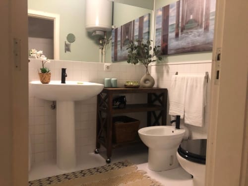 Banheiro PortoSense Almada com pia de pedestal, bidê, azulejo branco, móvel em madeira escura e acabamentos modernos