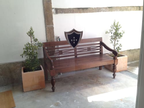 Banco de madeira com emblema de brasão no pátio exterior do apartamento PortoSense Almada no Porto, ladeado por plantas em vaso