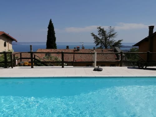 Kristallklarer Swimmingpool mit Ziegeldächern und Blick auf den Gardasee bei Casa Arianna, Salò Italien