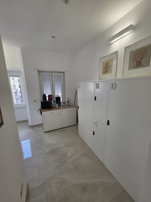 Corridoio moderno di B&B a Roma con armadi bianchi, zona scrivania, vista sulla città e servizi alberghieri