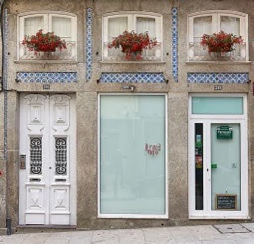 Fachada do apartamento PortoSense Almada no Porto com flores vermelhas nas janelas, azulejos azuis e portas brancas