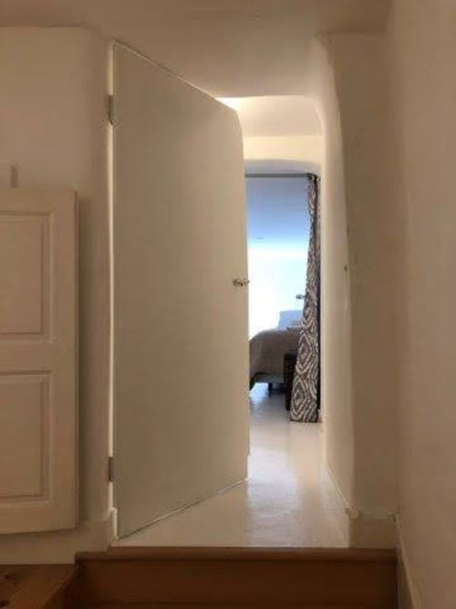 Corredor iluminado com porta branca aberta levando a um apartamento moderno em PortoSense Almada, Porto