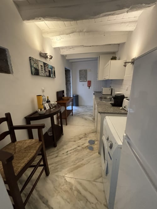 Cozinha moderna e sala de jantar do apartamento PortoSense Almada, Porto. Eletrodomésticos brancos, bancada de granito, cadeiras rústicas