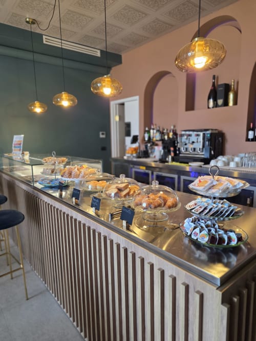 Banco panetteria moderno presso il Via del Mare Apulia B&B di Rutigliano con paste, lampade pendenti ambrate e vetrina di vini