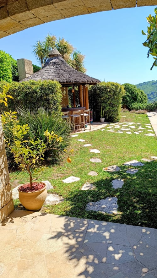 Strohdachpavillon im üppigen Garten des Loup Castel Boutique Hotel B&B, Le Bar-sur-Loup, umgeben von tropischen Pflanzen