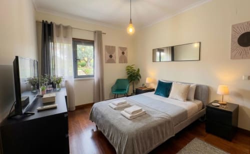 Quarto moderno no To Be Apartments em Lisboa com cama queen, vista para o jardim, TV e decoração contemporânea