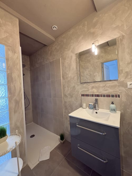 Salle de bain moderne à la Villa Aliénor aux Andelys avec vasque sombre, douche, miroir et radiateur-sèche-serviettes