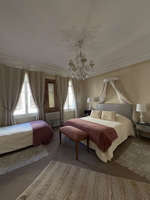Suite chambre élégante à la Villa Aliénor aux Andelys avec lit à baldaquin, lustre et vue sur la ville