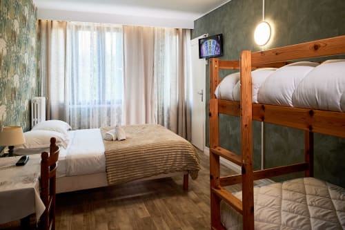 Family bedroom at La Caravelle hotel in Riom with double and bunk beds, wooden floors, and modern amenities
