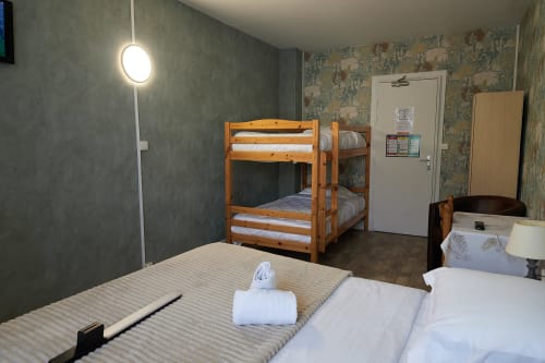 Family room at La Caravelle hotel in Riom with bunk bed, single bed, pendant light, and patterned wallpaper