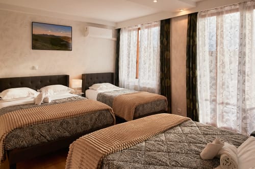 Spacious family room at La Caravelle hotel in Riom with three beds, dark headboards, and sheer curtains