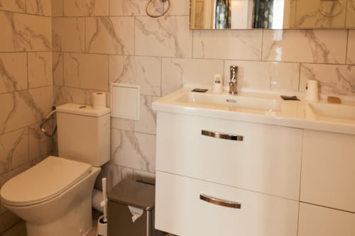Modern bathroom in La Caravelle hotel, Riom with white vanity, toilet, and marble-patterned tiles