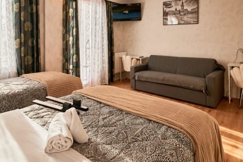 Spacious family room at La Caravelle hotel in Riom with two beds, sofa, wooden floors and modern amenities