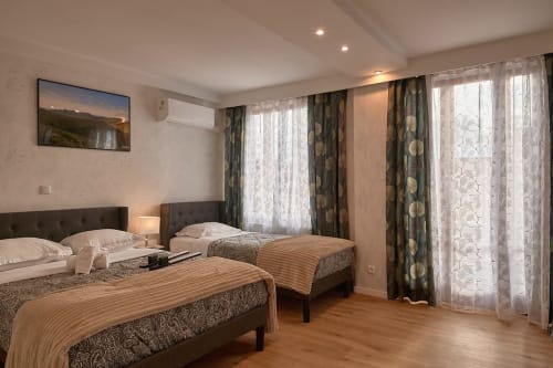 Family room at La Caravelle hotel in Riom with two beds, elegant decor, and patterned curtains