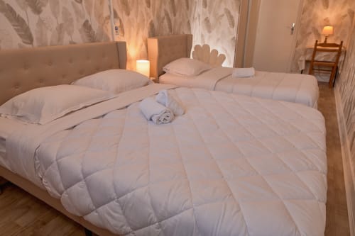 Triple bedroom at La Caravelle hotel in Riom with two beds, upholstered headboards, and warm lighting