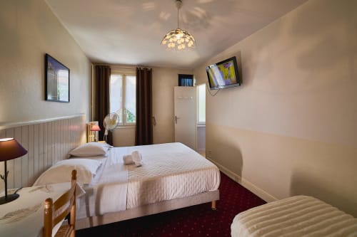 Triple bedroom at La Caravelle hotel in Riom with two beds, flat-screen TV, and modern amenities