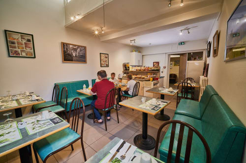 La Caravelle hotel breakfast room in Riom with turquoise seating, wooden tables, and guests dining