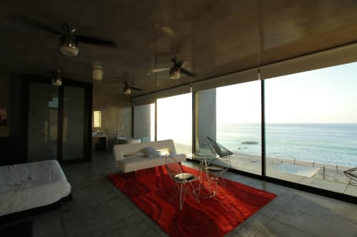 Dormitorio moderno frente al mar en Vidasoul BnB en La Vinorama, México, con vistas al océano, alfombra roja y muebles contemporáneos
