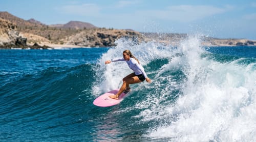 Surfista cabalgando una ola cerca de Vidasoul BnB en La Vinorama, México con costa rocosa