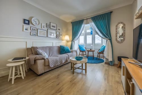Modern living room at Calm Holiday Homes in Marsa with beige sofa, turquoise accents, hardwood floors, and sea views from