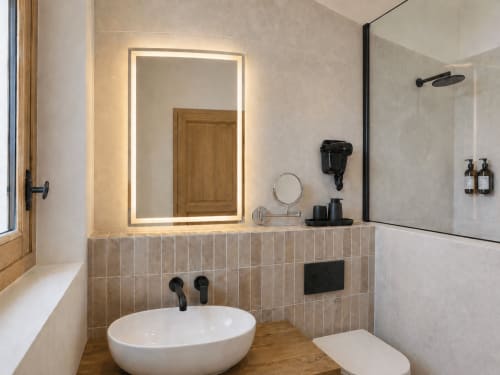 Modern bathroom in Le Palmier Aigues-Mortes with illuminated mirror, white vessel sink, and glass shower enclosure