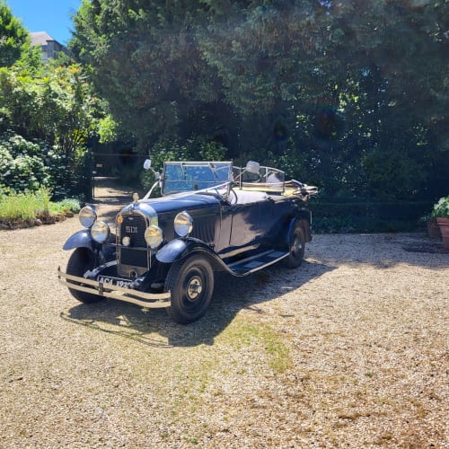 Voiture cabriolet vintage avec bagages garée au Logis des Tourelles, une charmante maison d'hôtes à Cognac, France