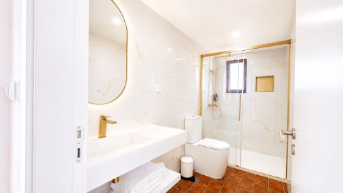 Banheiro de luxo na Suíte Deluxe 201 da Quinta das Susandas, Tresouras. Paredes em mármore, acabamentos dourados, chuveiro tipo walk-in.