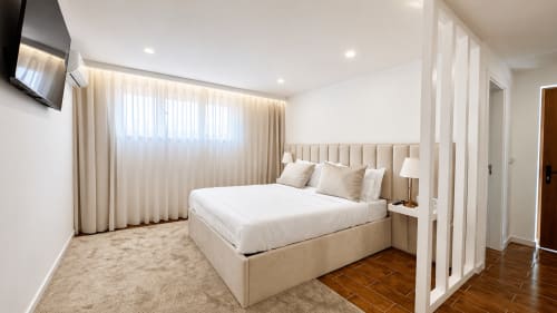 Espaçoso quarto de luxo na Quinta das Susandas com cama king, cabeceira estofada bege, cortinas creme e moderno