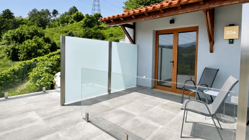 Terraço privado do Quarto Deluxe 204 da Quinta das Susandas com balaustrada de vidro, cadeiras de refeição e vista para a serra