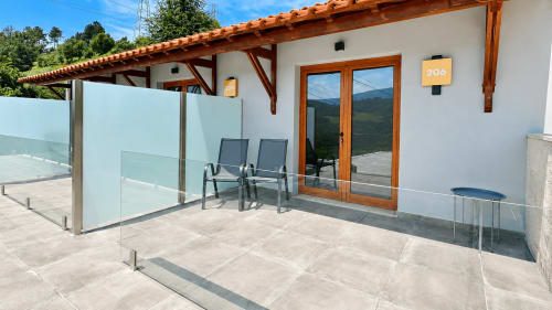Suíte deluxe 206 com terraço na Quinta das Susandas, Portugal, com guarda-corpo de vidro, espreguiçadeiras, pérgula de madeira e vistas de montanha