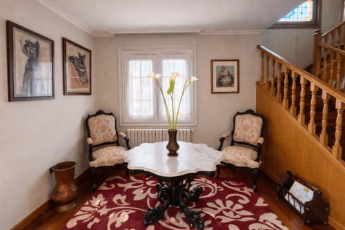 Elegante recibidor de la casa Mar y Sol en Baiona con mesa de mármol, alfombra estampada, sillas antiguas y escalera