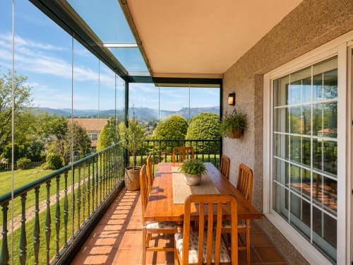 Terraza soleada con mesa de comedor de madera con vistas a montañas y jardines en la casa preciosa en Baiona