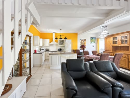 Spacieux salon de villa avec cuisine moderne, sièges en cuir noir et murs accent jaune vif à Sant Ambroggio