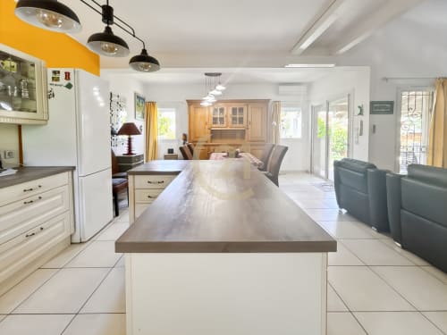 Cuisine moderne avec îlot, meubles crème et vue jardin dans une villa à L'Île-Rousse