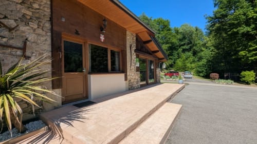 Entrée du gîte Les Grands Champs à Attignat-Oncin avec façade en pierre, porte en bois et terrasse dominant la propriété