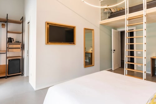 Moderna camera tripla presso Camere d'Aria B&B a Locana, Italia con letto bianco, specchi con cornice in legno, scaffali e vista montagna