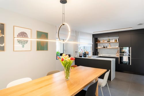 Zona cucina-pranzo moderna a Camere d'Aria a Locana con tavolo in legno, tulipani, armadiatura nera e luci a sospensione