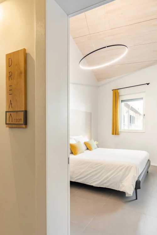 Camera da letto moderna a Camere d'Aria a Locana con letto bianco, dettagli gialli, lampada a sospensione e vista sulle montagne
