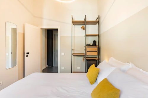 Camera da letto moderna a Camere d'Aria con biancheria bianca, cuscini gialli, scaffali minimalisti in metallo e vista sulle montagne
