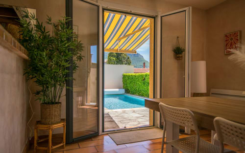 Millau villa with dining area, potted plant, open glass doors revealing private pool, terrace and mountain views