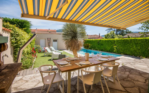 Villa à Millau avec piscine privée, auvent rayé jaune, table à manger, chaises longues et vue sur les montagnes