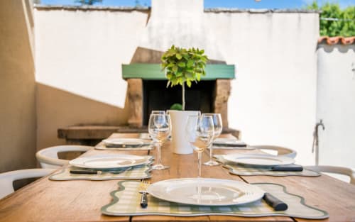 Outdoor dining table set with white plates, glasses and green accents at La Conciergerie villa in Millau